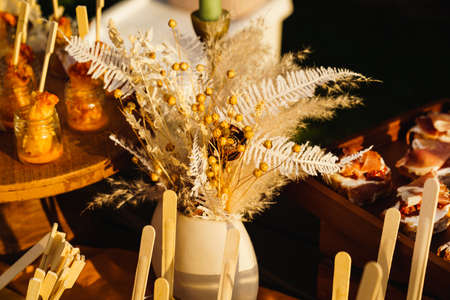 bouquet of dried flowers in a vase on the table with snacks.の写真素材