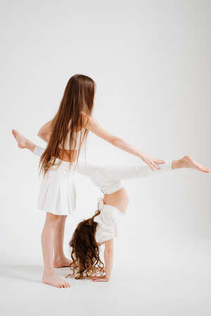two cheerful girls with long hair in white clothes play, have fun.