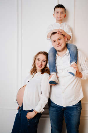 happy family. pregnant mother with her son and father in jeans and a white shirtの写真素材