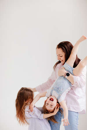 beautiful happy family in a white photo studio. Mom and two daughtersの写真素材