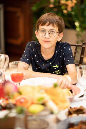 a teenage boy with glasses at the dinner table. childrens menu in restaurants.の写真素材