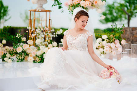 bride in the wedding ceremony area of live white and pink flowers.