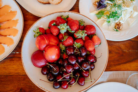 assorted fruit on a white plate on the dining table.