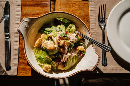 wooden table served with plates with salad and snacks, cutlery and glasses.の写真素材