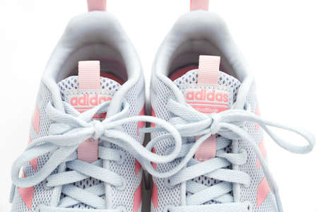 part of gray sports sneakers with pink stripes on a white background. adidas