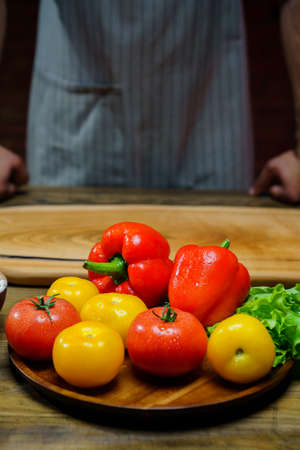 yellow and red tomatoes, lettuce and bell pepper with water drops. man in apron.の写真素材