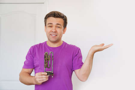 repairman of washing machine holds old tubular electric heaterの写真素材