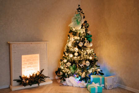 beautiful Christmas tree with a garland by the decorative fireplace in the room.の写真素材