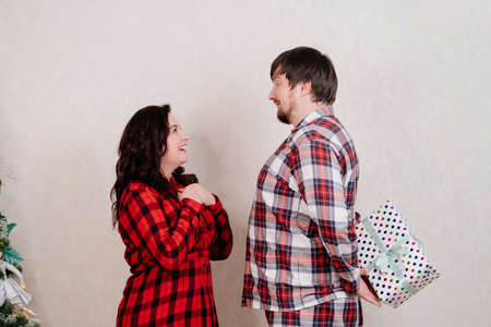 a man in plaid red pajamas makes a gift to a woman.の写真素材