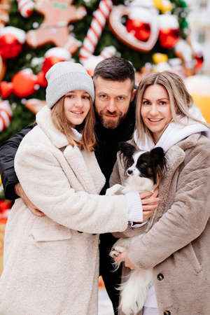the happy family on the winter streets with a dog papillon. New Yearの写真素材