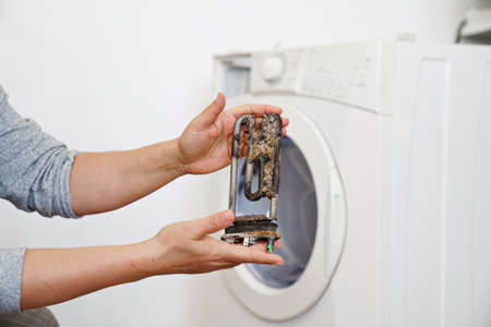 repair of washing machine. in hand old tubular electric heaterの写真素材