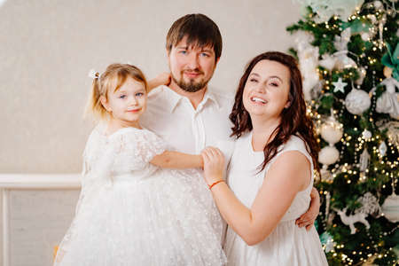 beautiful and happy family at the Christmas tree. mom, dad and daughterの写真素材