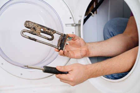 repair of washing machine. in hand old tubular electric heaterの写真素材