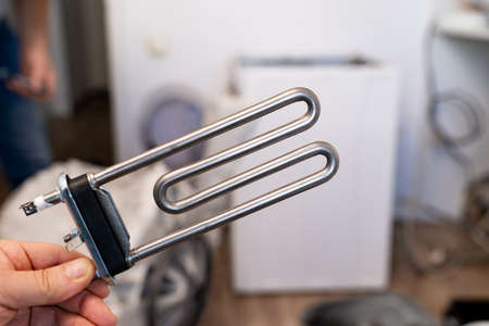 repair of washing machine. new tubular electric heater in hands of a repairmanの写真素材