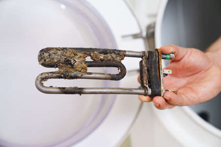repair of washing machine. in hand old tubular electric heaterの写真素材