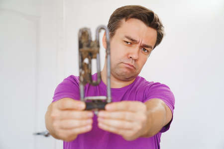 repairman of washing machine holds old tubular electric heater. selective focusの写真素材