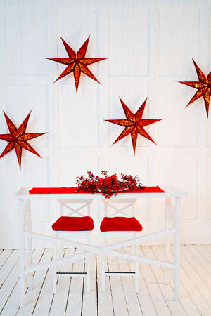 table is decorated for new year with red tablecloth, wreath and candles.の写真素材