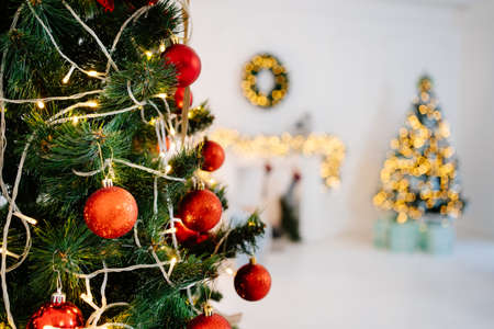 fragment of artificial Christmas tree with red decorations in white interior.の写真素材
