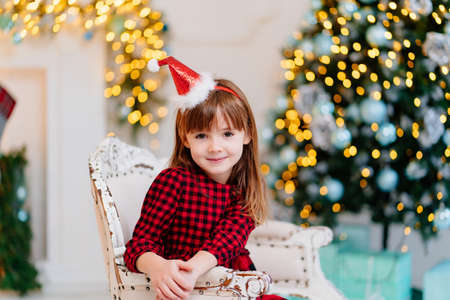 cute little girl in a red plaid dress and a cap in the New Years interior.の写真素材