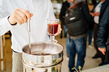 a man pours hot mulled wine into a glass. warming drinkの写真素材
