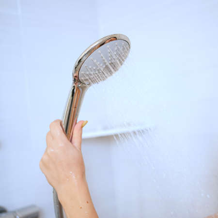 a shower can in a womans hand. plumbing for the bathroom.の写真素材