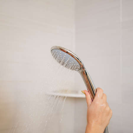 a shower can in a womans hand. plumbing for the bathroom.の写真素材