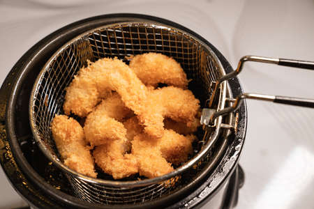 from the fryer pull out a basket with fried shrimp in batter.の写真素材