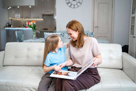 mother and daughter looking a book with photos from a family photo shootの写真素材