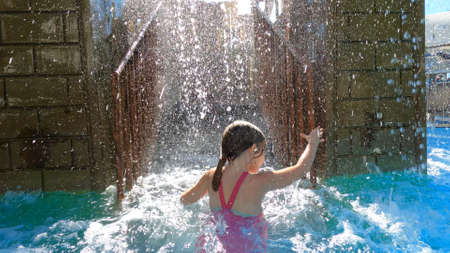 a girl in a pink swimsuit is climbs by the stairs to the water slide