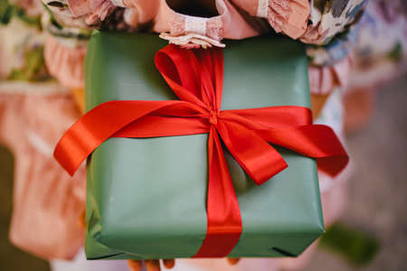 a box with a gift in green packaging paper with red ribbon.の写真素材