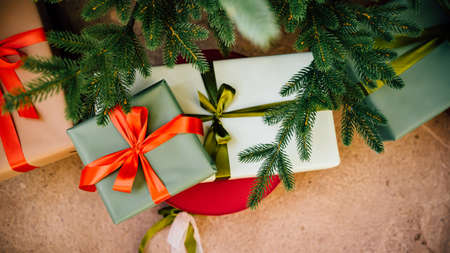 a boxes with red and green ribbon under the christmas treeの写真素材