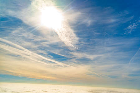 the sky above the clouds in flight on an airplane through a window.