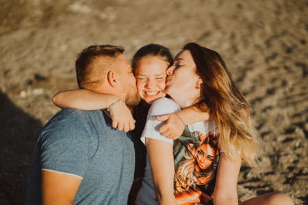 kiss. happy family on beach. mom, dad and daughter on vacation at seaside resortの写真素材