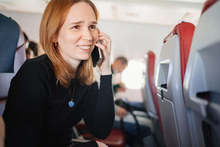 woman is talking on the phone in a seat on board the plane. wifi for passengersの写真素材