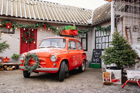 a red little car with a Christmas wreath by the porch of the house.のeditorial素材