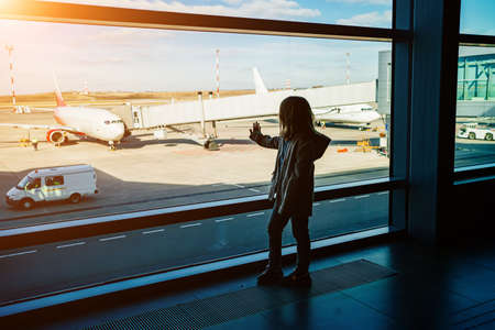 a silhouette little girl standing by the window at the airport.の写真素材