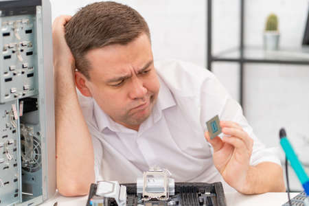 computer workshop. professional services. sad repairman with a processor in hand