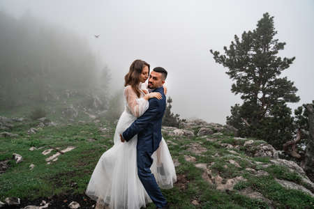 newlyweds walk cuddling in misty mountain forest. wedding on trip