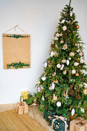 Christmas tree in eco style with boxes of gifts against background of white wallの写真素材