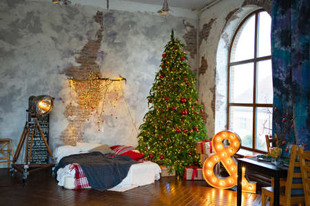 a Christmas tree in bedroom by bed with lamp shaped sign and in loft interior.の写真素材