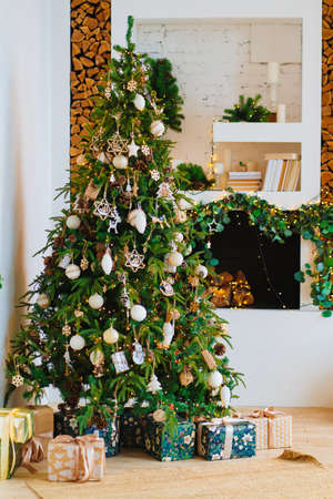 a large Christmas tree with boxes of gifts by the decorative fireplaceの写真素材