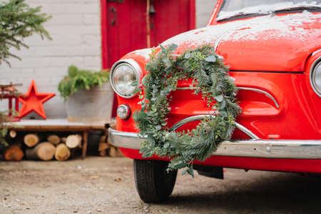 a red little car with a Christmas wreath by the porch of the house.の写真素材