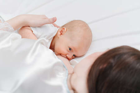 breastfeeding. close up. mother feeds the baby with breast milk lying in bedの写真素材