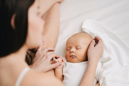 mom in bed next to a sleeping baby. the happiness of motherhood.の写真素材