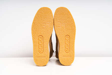 non-slip outsoles of two brown leather winter boots on a white background