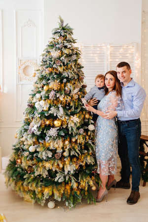happy and beautiful mom, dad and little son decorate the Christmas tree.の写真素材