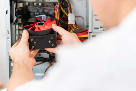 computer workshop. hand of repairman installs a cooler in in a computer
