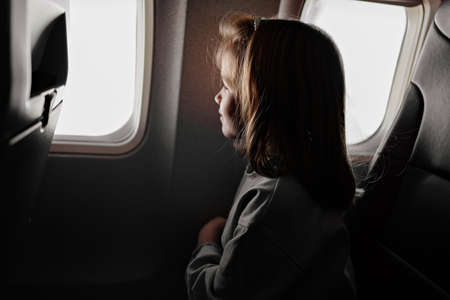 a little girl sits in an airplane seat by the window.の写真素材