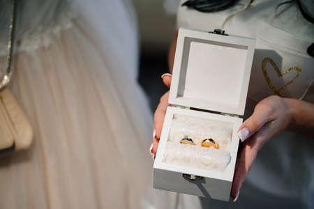 a white box with wedding rings in womens hands.の写真素材