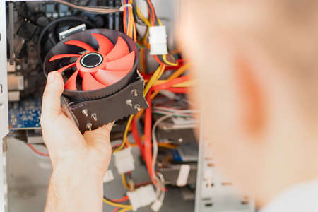 computer workshop. hand of repairman installs a cooler in in a computer